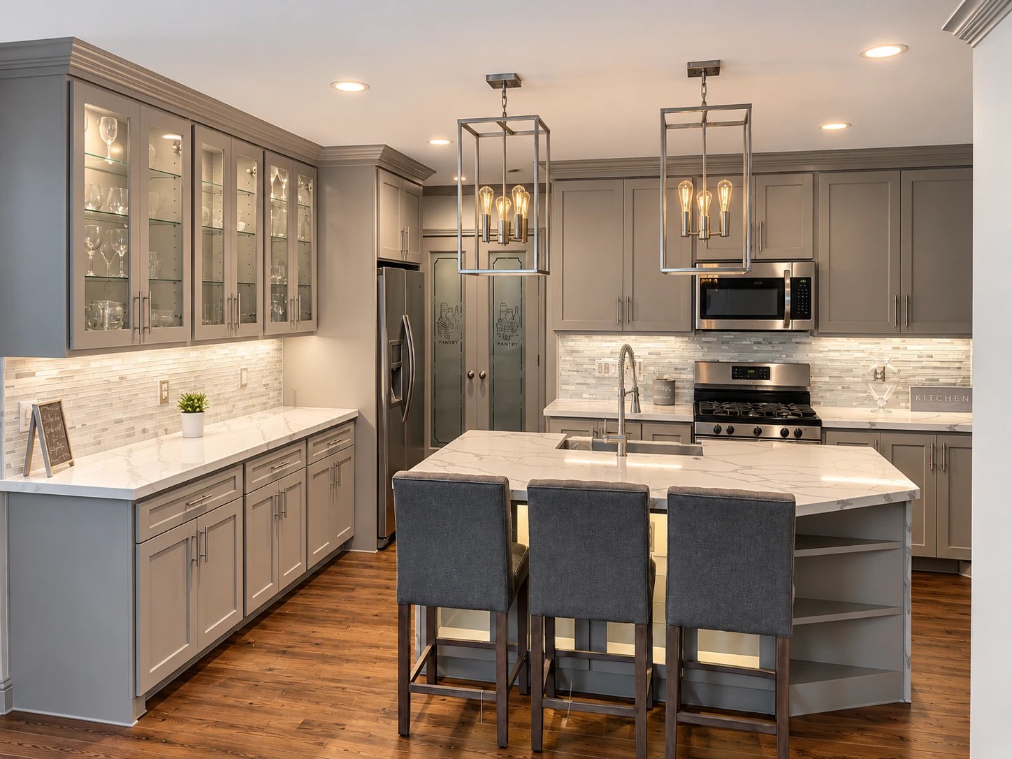 Remodeled kitchen with gray shaker cabinets, quartz island and pendant lighting